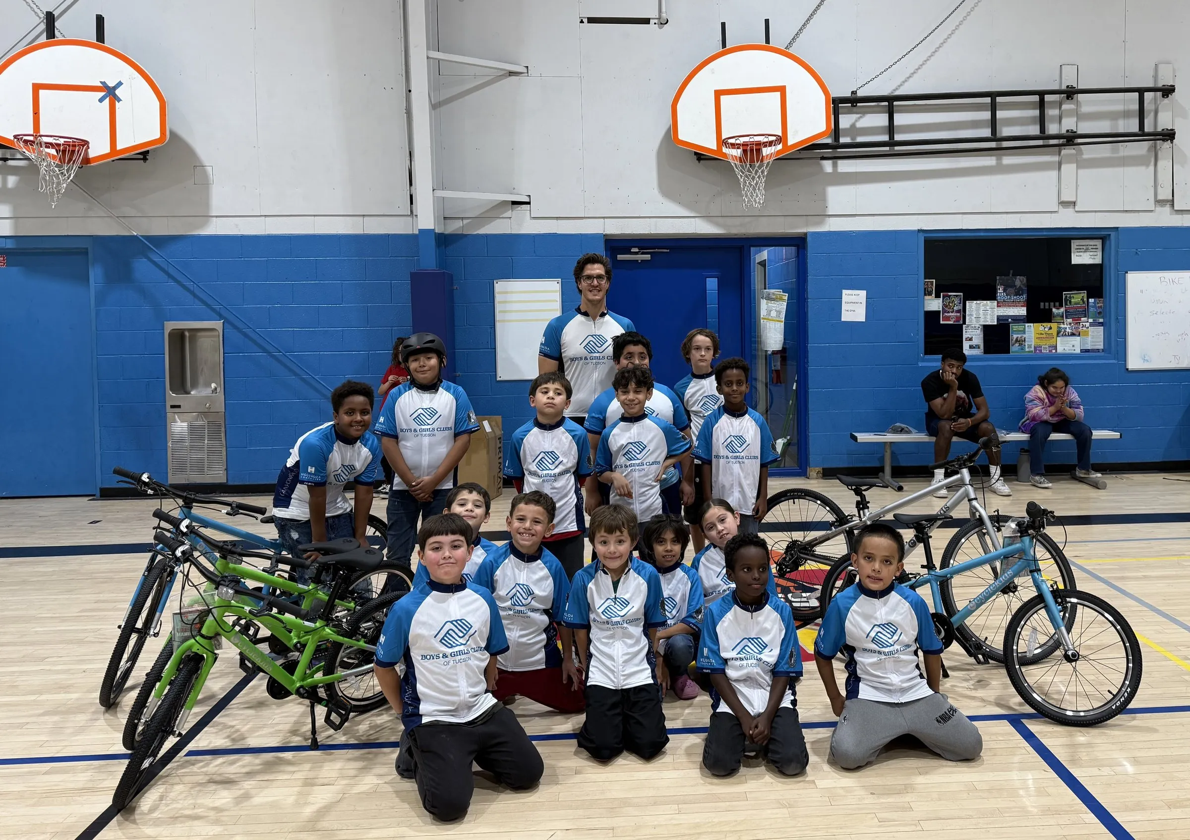 A Boys and Girls Clubs of Tucson team in cycling jerseys, standing with their bikes.