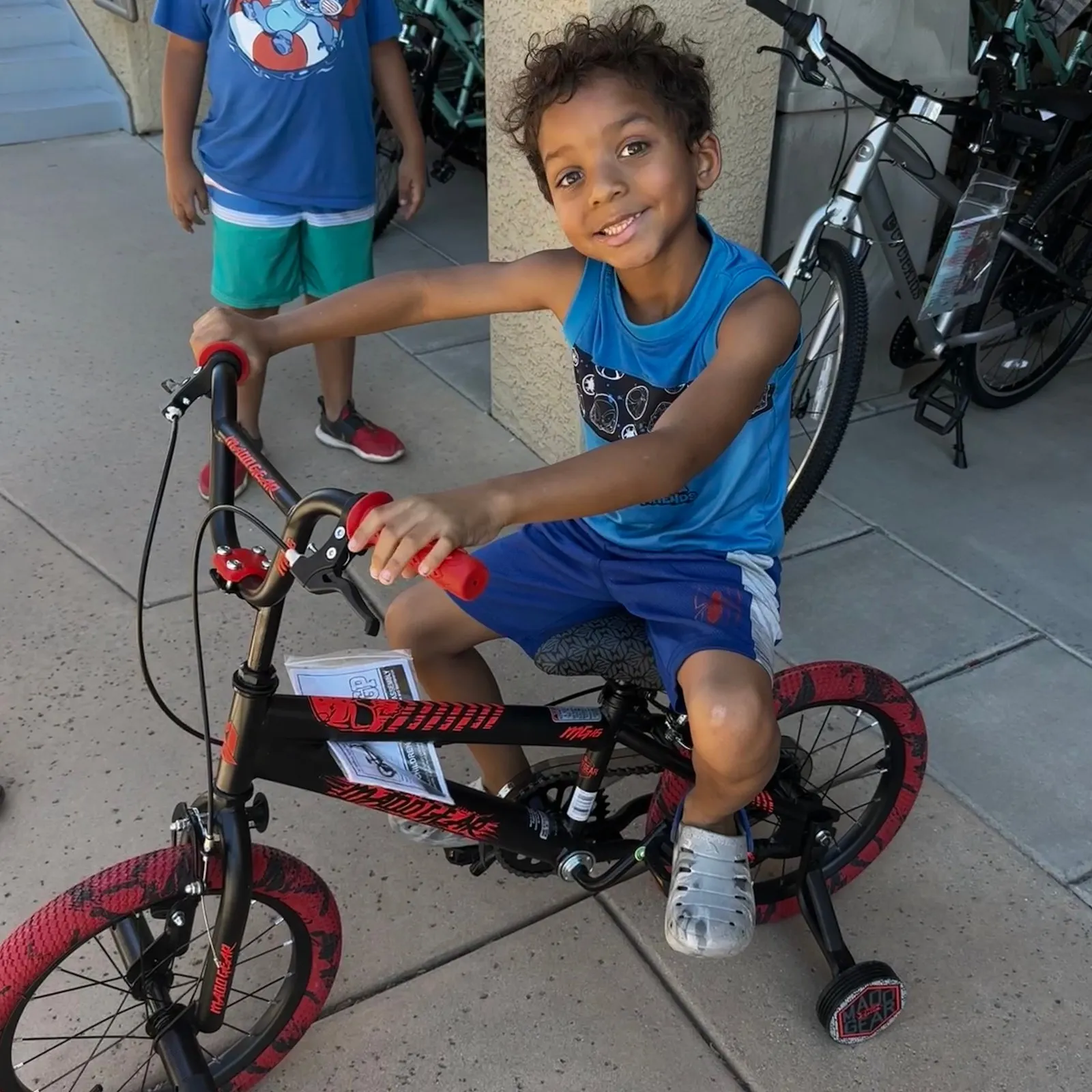 A boy sitting on a brand-new bike, the assembly paperwork still tied to the frame, grinning at the camera